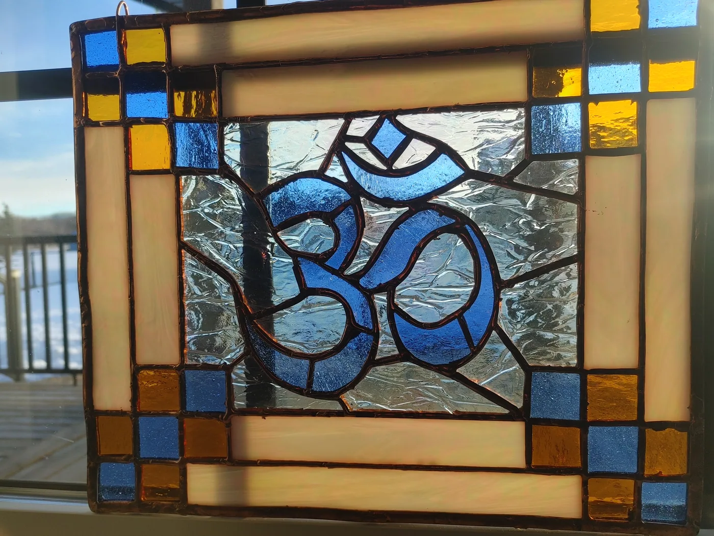 Framed stained-glass Om symbol installed in a window
